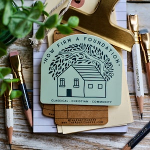 May include: A green and white sticker with a house and a tree. The text on the sticker reads "How Firm A Foundation. Classical - Christian - Community".