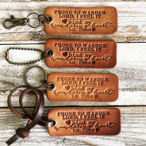 May include: Four brown leather keychains with a metal ring and a leather strap. Each keychain has the same text: "PRONE TO WANDER LORD, I FEEL IT bind my wandering heart to Thee".