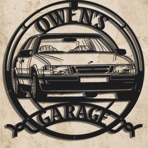 May include: Black metal garage sign featuring a car silhouette within a circular frame. The words "OWEN'S" are arched above the car, and "GARAGE" is arched below. The sign is designed to be mounted on a wall.