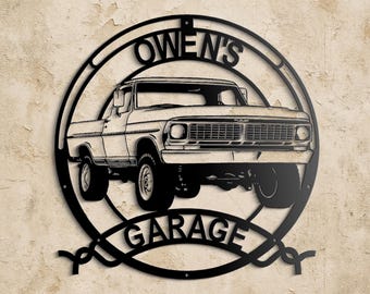 Op de afbeelding: Zwart metalen bord met een klassiek pick-up truck ontwerp. Het bord is cirkelvormig met de woorden "OWEN'S GARAGE" uitgesneden. De truck staat in het midden, wat een vintage uitstraling geeft aan de garage decoratie.