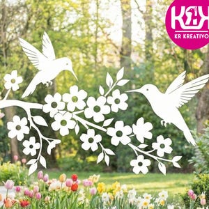 Op de afbeelding: Witte raamsticker met kolibrie en bloementak. De sticker toont twee kolibries en een tak met bloemen. De achtergrond toont een tuin met kleurrijke bloemen en groen.