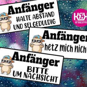 Op de afbeelding: Drie witte rechthoekige borden met zwarte tekst en een cartoon luiaard met zonnebril en baseballpet. De borden luiden "Anfänger" met verschillende zinnen: "HALTE ABSTAND UND SEI GEDULDIG", "hetz mich nicht!" en "BITTE UM NACHSICHT".