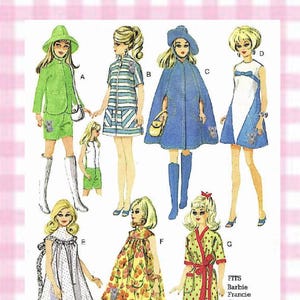 May include: A vintage sewing pattern illustration featuring seven outfits for dolls labeled A through G. The designs include a green suit, striped dress, blue cape, white and blue dress, polka dot gown, floral dress, and a red-spotted robe with text.