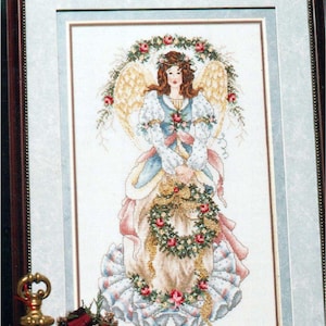 May include: Framed cross-stitch of an angel with brown hair, wearing a blue and white dress, holding a wreath of roses. The angel has gold wings and is surrounded by a floral wreath. The frame is dark brown.