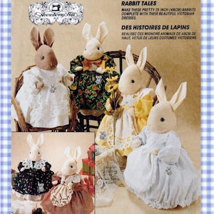 May include: A collection of six plush rabbit dolls, each 15 inches tall, wearing Victorian-style dresses. The rabbits are depicted in various outfits, including white, floral, yellow, blue, black, and brown dresses with lace details.