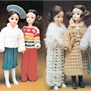 May include: Dolls wearing handmade knitted and crocheted clothing. The dolls are dressed in sweaters, skirts, trousers, and coats in colours such as white, red, blue, and tan. Some dolls have hats and boots.