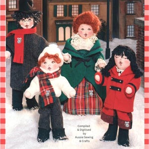 May include: Four fabric dolls dressed in winter clothing stand in snow. One wears a black coat and top hat with a red scarf. Another wears a white sweater and plaid scarf. A third wears a green coat and plaid skirt. The fourth wears a red coat.