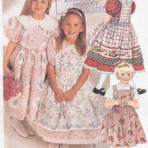 May include: Image of a sewing pattern showing three children's dresses. The dresses feature floral, watermelon, and plaid patterns. The dresses are in pink, red, and white. The image includes the text "Lincraft."