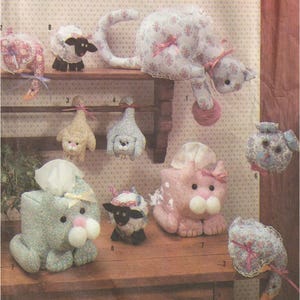 Könnte beinhalten: Eine Sammlung handgefertigter Taschentuchbox-Überzüge mit verschiedenen Tiermotiven, darunter Katzen, Schafe und Hunde. Die Überzüge sind aus Stoff mit Blumenmustern und haben gestickte Details.