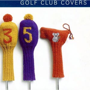 May include: Knitted golf club covers in various colors, including orange, yellow, and purple. Some covers feature numbers 1, 3, and 5, while others have a koala or text. Each cover has a pom-pom on top.