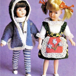 May include: Two dolls dressed in knitted clothing. The left doll has dark hair, a blue hooded jacket with white trim, and blue and white striped pants. The right doll has blonde hair with red bows, a white blouse, and a green dress with a red apron.