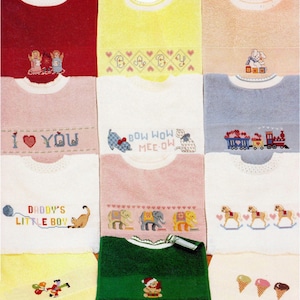 Könnte beinhalten: Eine Auswahl an Baby-Lätzchen in verschiedenen Farben wie Rot, Gelb, Rosa und Grün. Jedes Lätzchen ist mit gestickten Motiven wie Engeln, Herzen, Katzen, Elefanten, Zügen, Schaukelpferden und Eiswaffeln verziert. Einige Lätzchen tragen Texte wie "I ❤️ YOU" und "DADDY'S LITTLE BOY."