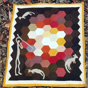 Pode incluir: Um edredão feito à mão com um padrão central em favo de mel em tons de branco, amarelo, laranja, vermelho e roxo. A borda é marrom escuro com figuras brancas de uma pessoa e animais. O edredão tem uma borda amarela e branca.