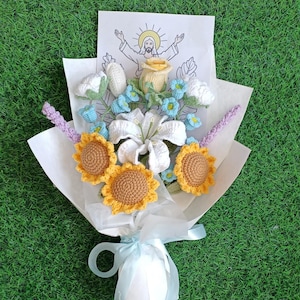 Puede incluir: Un ramo de flores de ganchillo envuelto en papel blanco. El ramo incluye girasoles, lirios, rosas y nomeolvides. Se incluye una peque&ntilde;a tarjeta con un dibujo de Jes&uacute;s.