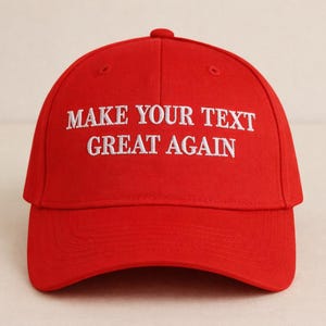 May include: A vibrant red baseball cap with a curved peak. The cap displays the white embroidered text "MAKE YOUR TEXT GREAT AGAIN" across the front. It has a rounded crown and a small button at the top.