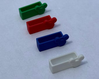Puede incluir: Cuatro pequeños recipientes rectangulares de colores verde, rojo, azul y blanco, cada uno con un diseño de cabeza de Mickey Mouse. Los recipientes están dispuestos en diagonal sobre un fondo liso.