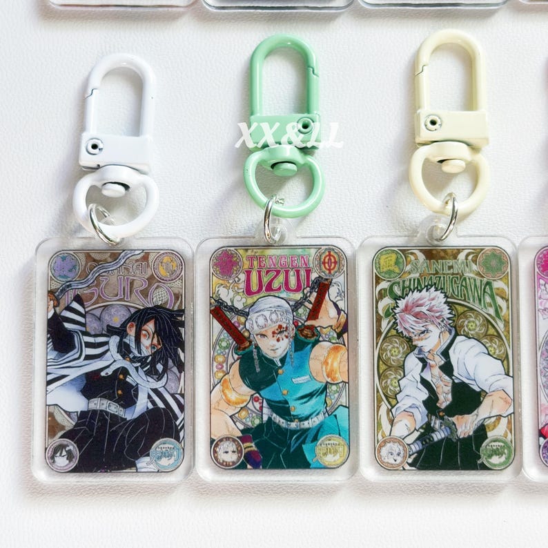 K&ouml;nnte beinhalten: Acryl-Schl&uuml;sselanh&auml;nger mit farbenfrohen Illustrationen von Anime-Charakteren. Jeder Schl&uuml;sselanh&auml;nger hat einen Metallverschluss in Wei&szlig;, Gr&uuml;n oder Creme. Die Schl&uuml;sselanh&auml;nger zeigen die Namen der Charaktere und sind rechteckig.