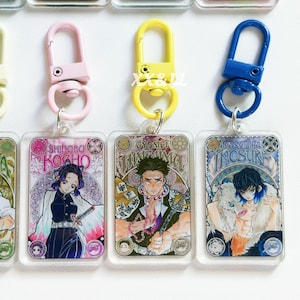 K&ouml;nnte beinhalten: Acryl-Schl&uuml;sselanh&auml;nger mit Anime-Charakteren mit farbenfrohen Designs. Jeder Schl&uuml;sselanh&auml;nger hat einen anderen Charakter mit einem farblich passenden Verschluss in Rosa, Gelb und Blau. Die Schl&uuml;sselanh&auml;nger tragen die Namen der Charaktere.