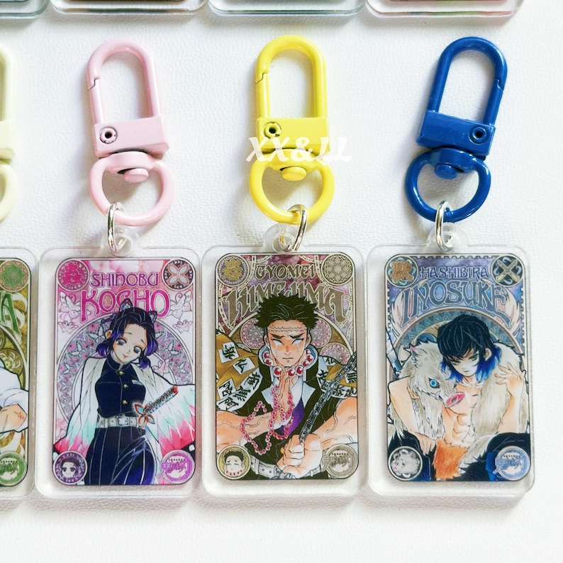 K&ouml;nnte beinhalten: Acryl-Schl&uuml;sselanh&auml;nger mit Anime-Charakteren mit farbenfrohen Designs. Jeder Schl&uuml;sselanh&auml;nger hat einen anderen Charakter mit einem farblich passenden Verschluss in Rosa, Gelb und Blau. Die Schl&uuml;sselanh&auml;nger tragen die Namen der Charaktere.