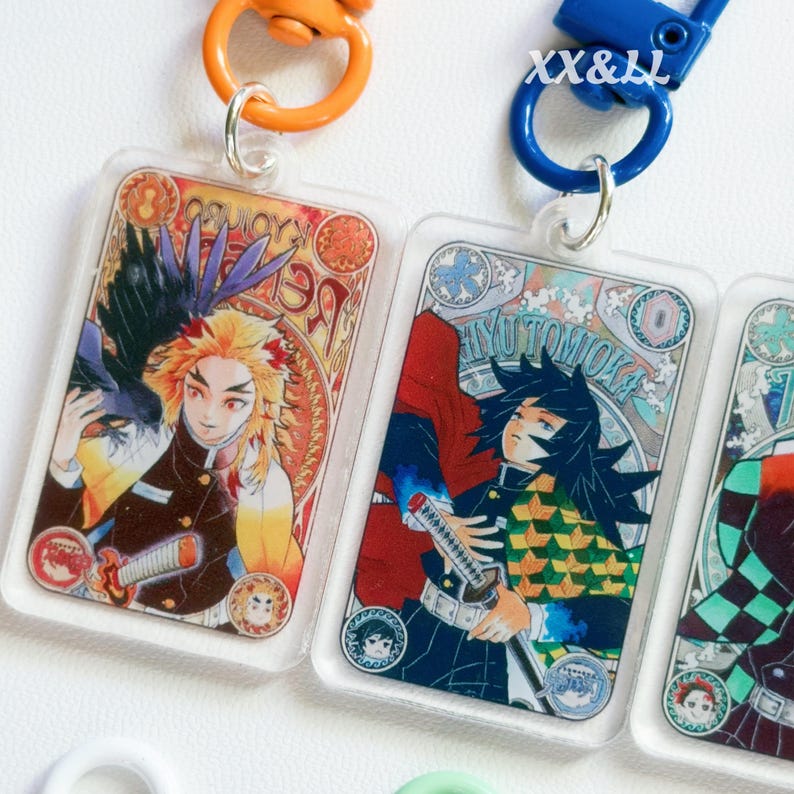 K&ouml;nnte beinhalten: Rechteckige Schl&uuml;sselanh&auml;nger aus Acryl mit farbenfrohen Illustrationen von Anime-Charakteren. Jeder Schl&uuml;sselanh&auml;nger hat einen silberfarbenen Ring und einen farbigen Verschluss. Die Schl&uuml;sselanh&auml;nger zeigen detaillierte Kunstwerke von Charakteren der Anime-Serie.