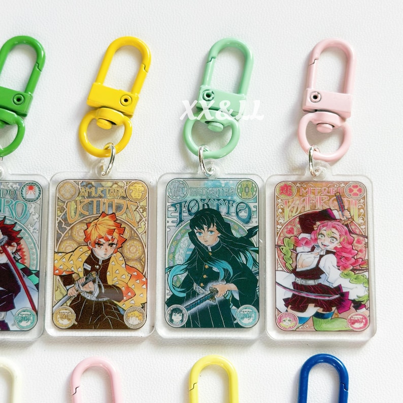 K&ouml;nnte beinhalten: Acryl-Schl&uuml;sselanh&auml;nger mit Anime-Charakteren mit farbenfrohen Designs. Jeder Schl&uuml;sselanh&auml;nger hat eine rechteckige Form mit einem Metallverschluss in verschiedenen Farben, darunter Gr&uuml;n, Gelb und Rosa. Die Schl&uuml;sselanh&auml;nger zeigen detaillierte Illustrationen von Anime-Charakteren.