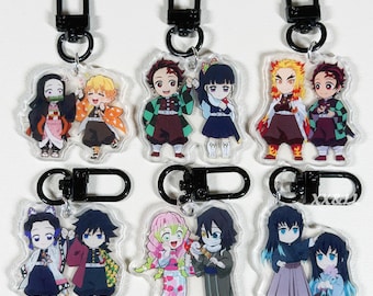 May include: Nine acrylic keychains featuring anime characters with black metal clasps. The keychains showcase various characters in colorful outfits, with detailed facial expressions and poses. Each keychain is approximately 2 inches in height.