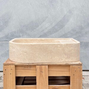 Side angle view showing smooth exterior surface of travertine sink