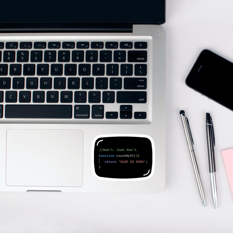 May include: A black sticker with a white border, displaying computer code and the text "//Don't. Just don't. function touchMyPC(){ return 'SLAP SO HARD'; }", is placed on a laptop. A smartphone and two pens are also visible.