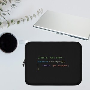 以下が含まれることがあります： 「//Don't. Just don't. function touchMyPC(){ return 'get slapped'; }」というテキストがカラフルなコードのようなフォントで書かれた黒いラップトップスリーブ。シルバーのノートパソコン、白いコーヒーマグ、緑の植物が背景にあります。