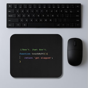 May include: A black computer mouse and a black rectangular mousepad with the text "//Don't. Just don't. function touchMyPC(){ return 'get slapped'; }" are next to a black keyboard. The keyboard is on a white surface.