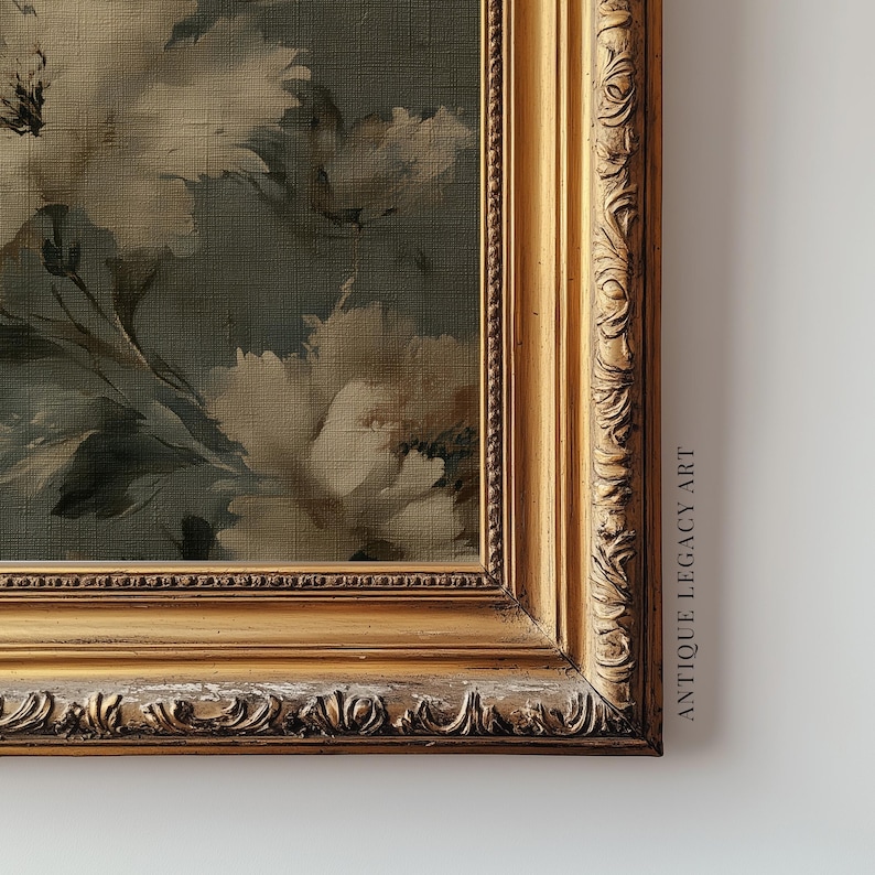 Op de afbeelding: Een ingelijste bloemenprint met een gouden, sierlijke lijst. Het kunstwerk toont grote, zachte witte bloemen tegen een gedempte teal achtergrond. De lijst heeft gedetailleerde gravures en de tekst "ANTIQUE LEGACY ART" is zichtbaar.
