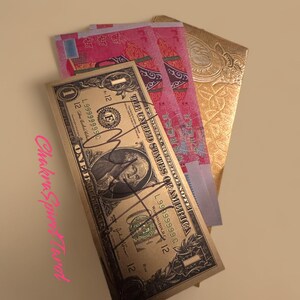 May include: A gold-colored $1 bill with a portrait of George Washington. The bill is folded in half and placed on top of three red and blue paper envelopes with Chinese characters. The envelopes are folded in half and have a gold-colored design.
