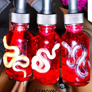 May include: Three small glass bottles with red liquid and a white snake design. The bottles have silver droppers and are labeled "Removal of 3rd Party Combined Deadly Attraction".