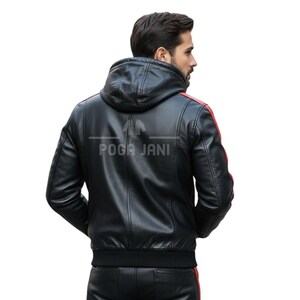 May include: Black leather jacket with a hood and red stripes on the shoulders. The jacket has a ribbed hem and cuffs. The text "POGA JANI" is printed on the back of the jacket.