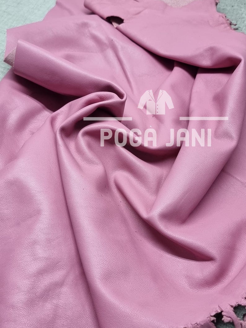 May include: A sheet of pink leather with a textured surface. The leather is folded and draped, showing its flexibility. The text "POGA JANI" is visible on the leather.