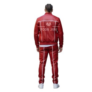May include: A red leather tracksuit with white stripes and trim. The jacket has a bomber style with white accents and the text "POGA JANI". The pants have a straight leg design. The person is wearing white sneakers.