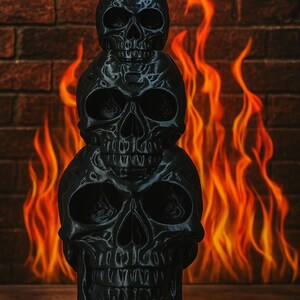 May include: A black, three-skull sculpture with a flat base. The skulls are stacked, with the top one having a small, flat top. The background features a brick wall and flames, creating a spooky, Halloween-themed aesthetic.