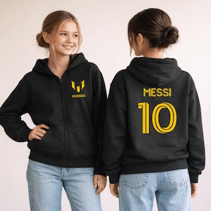 May include: Black zip-up hoodie with gold lettering and logo. The front features a gold logo and the word "MESSI". The back displays "MESSI" above the number "10" in gold. The hoodie is worn with blue jeans.