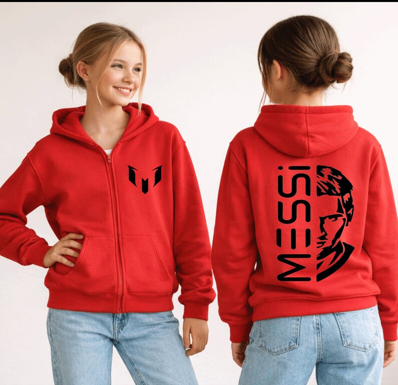 Puede incluir: Una sudadera con capucha y cremallera de color rojo brillante con un logotipo negro en el pecho izquierdo. La parte posterior muestra el texto MESSI verticalmente junto a una ilustraci&oacute;n gr&aacute;fica negra de un rostro. Incluye capucha, mangas largas y dos bolsillos.