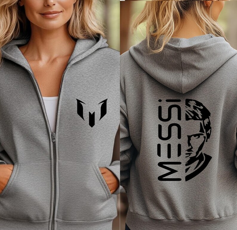 Puede incluir: Una sudadera con capucha y cremallera en color gris jaspeado con un logotipo negro en el pecho izquierdo. La parte posterior muestra el texto MESSI en letras negras grandes junto a una ilustraci&oacute;n gr&aacute;fica negra estilizada de un rostro.