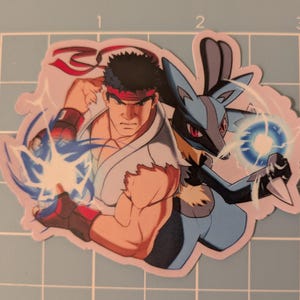 May include: A sticker featuring two characters: a muscular man in a white gi with a red headband and a blue and black creature. The man is throwing a blue energy blast, and the creature is holding a blue energy ball.