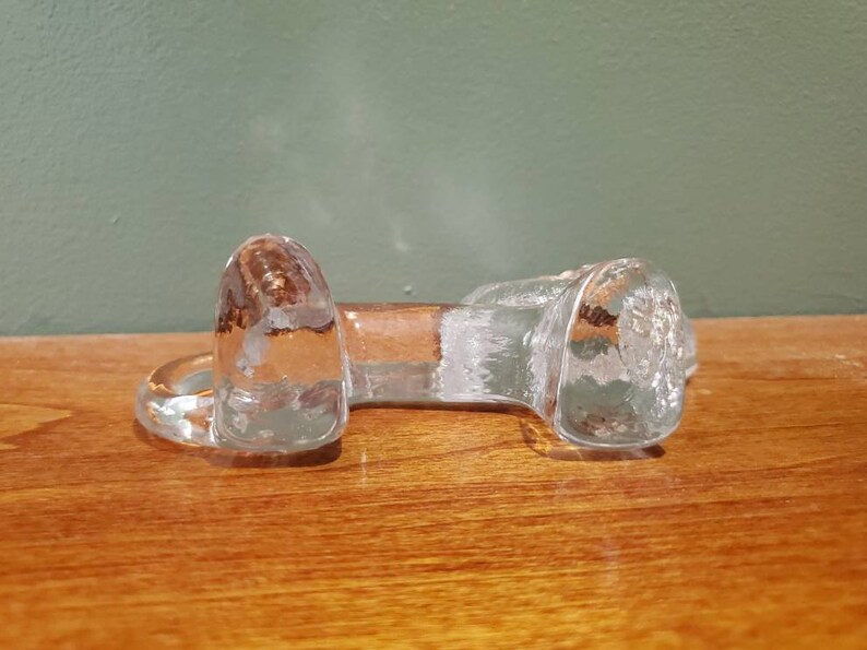May include: A clear glass bottle stopper shaped like a dog bone.
