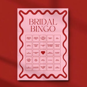 Könnte beinhalten: Eine rosafarbene Braut-Bingo-Karte mit einem roten Herzen in der Mitte. Die Karte hat 25 Felder mit verschiedenen Fragen über die Braut und den Bräutigam. Der Text "Bridal Bingo" steht oben auf der Karte.