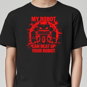 May include: Black t-shirt with a red graphic of a robot and the text "MY ROBOT CAN BEAT UP YOUR ROBOT". The robot design has a square head, angry eyes, and a blocky body. The text and robot are in a distressed style.