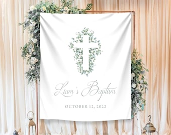 May include: White backdrop with a green leafy cross design and the text "Liam's Baptism" with the date "October 12, 2022".