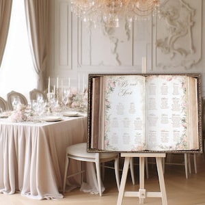A beautiful open storybook seating chart featuring pale blush pink florals on the pages with Be Our Guest and your custom seating chart printed in an elegant vintage gold font. Great for a fairytale wedding or for a Once Upon a Time celebration.