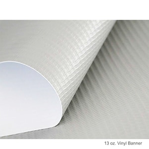 May include: A rolled-up, off-white vinyl banner with a textured surface. The banner has a white interior and the text "13 oz. Vinyl Banner" at the bottom.
