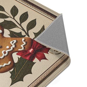 May include: A brown gingerbread cookie with white icing and the words "Gingerbread" written on it. The cookie is decorated with a red bow and is surrounded by green holly leaves.