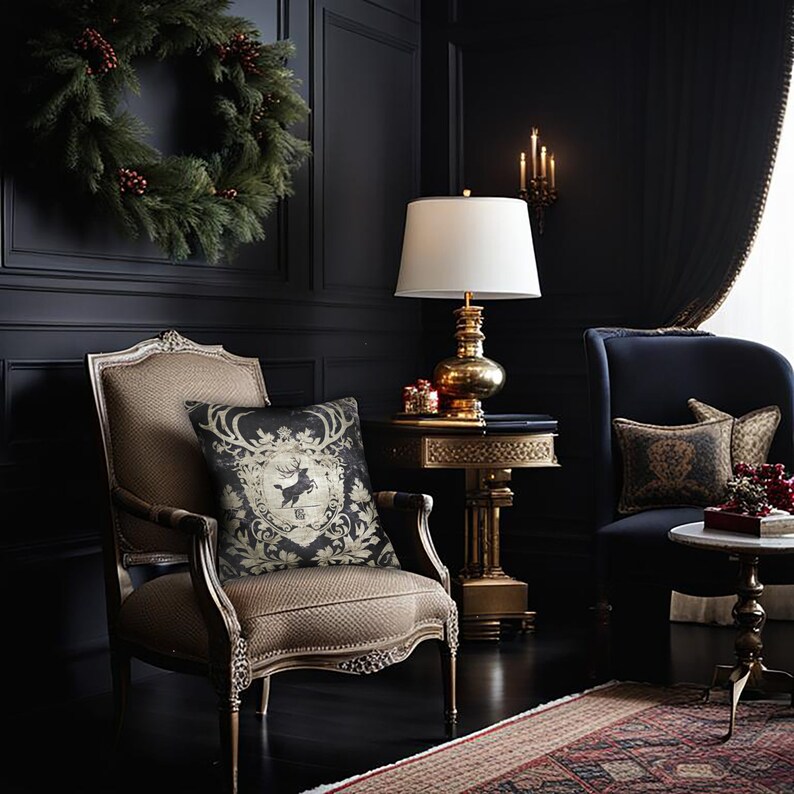 May include: A dark living room with a black and gold patterned throw pillow on a brown armchair. A gold table lamp with a white shade sits on a gold side table. A dark blue armchair with a gold patterned throw pillow sits in the background.