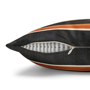 May include: A black and orange striped throw pillow with a zipper closure. The pillow has a white and gray striped lining.